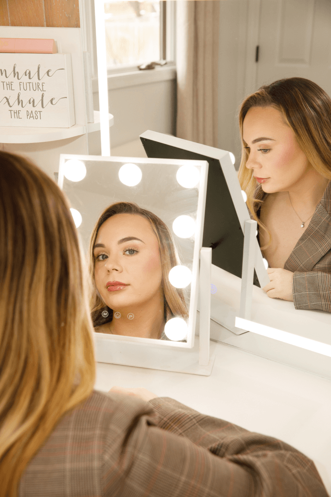 Mary Scott, President & CEO of MSM Beauty Solutions, sitting at a vanity mirror in a plaid blazer, reflecting on her role as a beauty industry product developer and project manager dedicated to bringing cosmetics and skincare products to market.