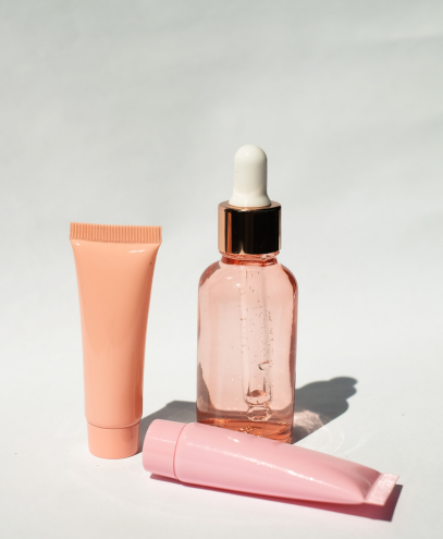 Minimalist flat lay of pink cosmetic packaging including a serum dropper bottle and tubes, representing MSM Beauty Solutions’ product development expertise in creating intentional and innovative beauty products with streamlined project management.